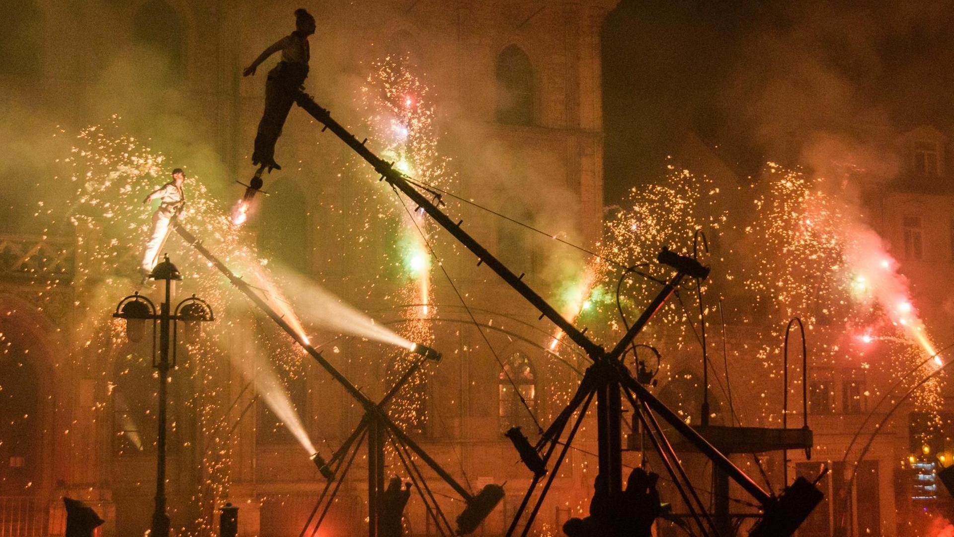 Schatten von Tänzern und Ölpumpen vor Feuerwerk. Das Aktionstheater PAN.OPTIKUM eröffnet am 18.08.2017 auf dem Markt in Weimar (Thüringen) das Kunstfest 2017 mit dem Stück »Transition«.