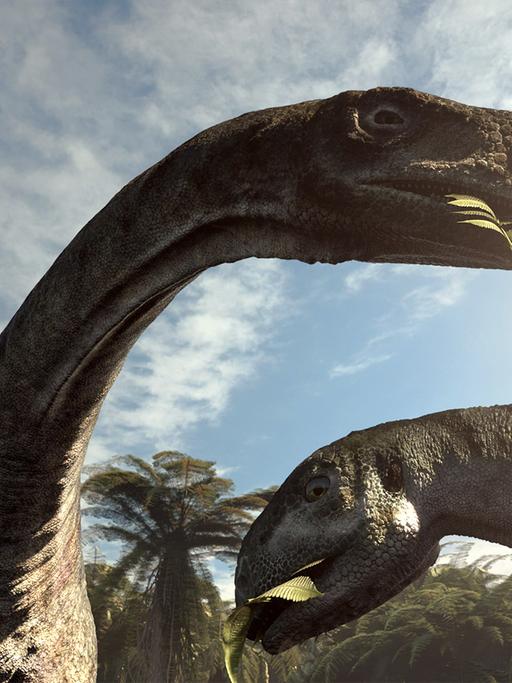 Zwei Dinosaurier in einer Filmszene, Hälse ragen in den Himmel, sie essen Blätter