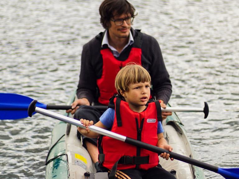 Ein Mann macht mit einem Jungen eine Bootstour.