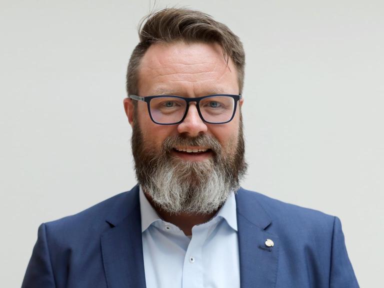 Der Rostocker Oberbürgermeisterkandidat Claus Ruhe Madsen schaut in die Kamera. Er hat einen Seitenscheitel und einen Vollbart.