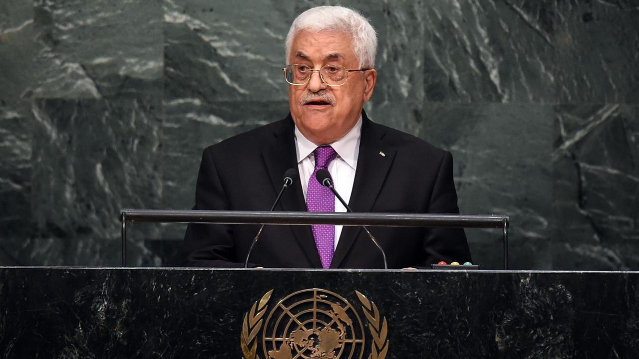 Abbas steht am Rednerpult vor einer Wand aus grau-weißem Marmor und spricht. Das Pult ziert ein goldfarbenes Emblem der Vereinten Nationen. 