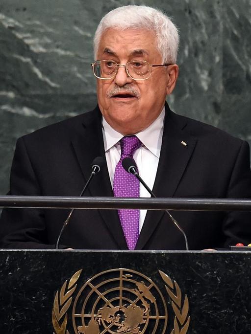 Abbas steht am Rednerpult vor einer Wand aus grau-weißem Marmor und spricht. Das Pult ziert ein goldfarbenes Emblem der Vereinten Nationen.