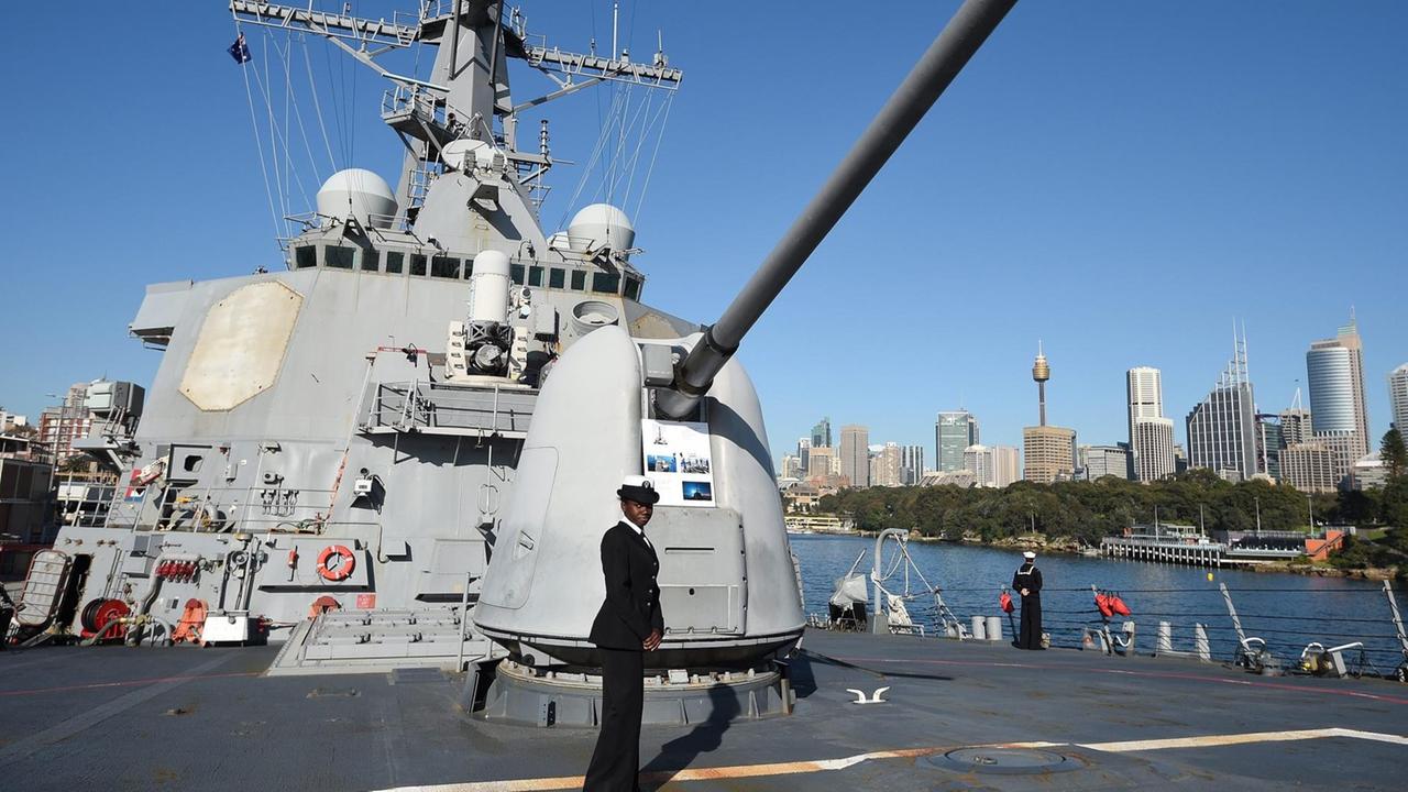 Auf dem Deck vor einer Haubitze steht eine dunkelhäutige Matrosin. 