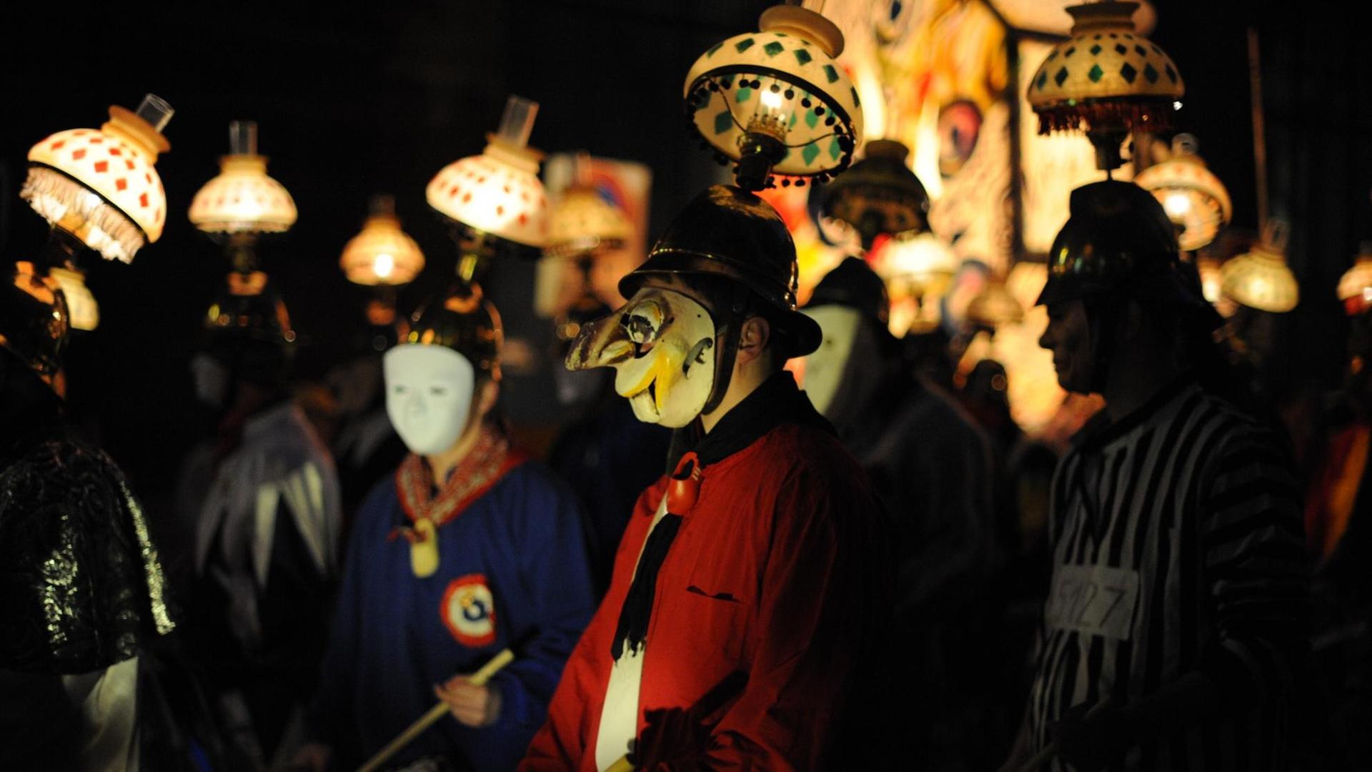 Teilnahmer der Morgestraich zum Auftakt der Basler Fasnacht mit Masken und Laternen Teilnahmer der Morgestraich zum Auftakt der Basler Fasnacht mit Masken und Laternen