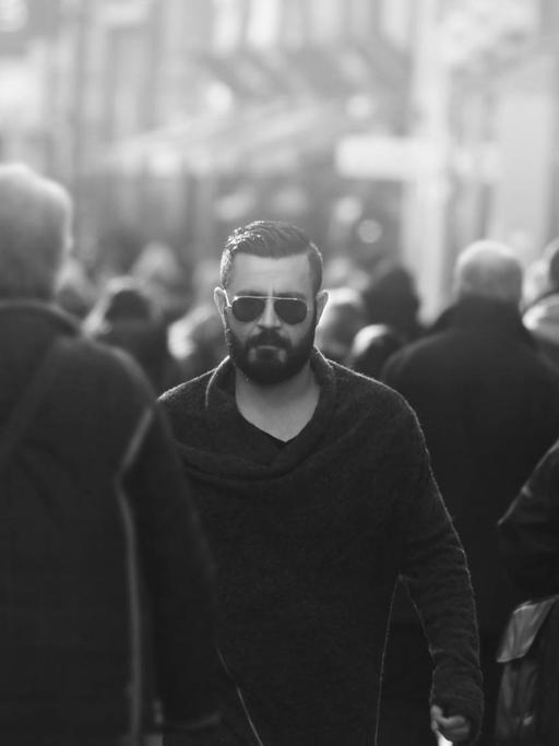 Shahin Najafi, ein junger Mann mit Bart und Sonnenbrille, geht durch eine Menschenmenge