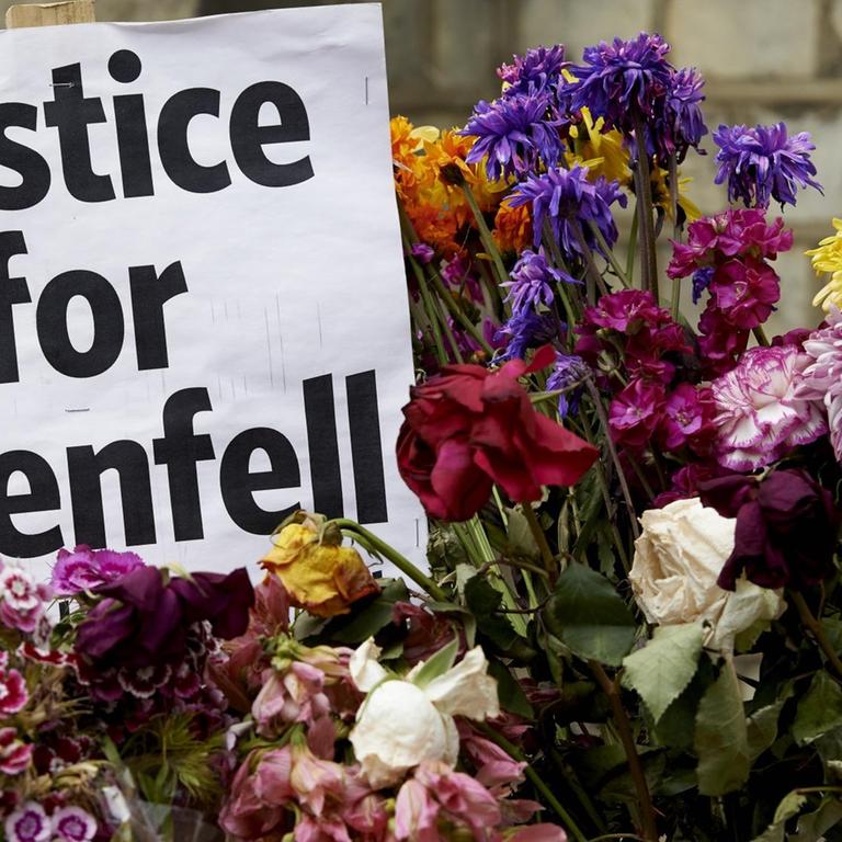 In Erinnerung an die Brandkatastrophe im Grenfell Tower in London stehen Blumen neben einem Zettel mit der Aufschrift "Justice for Grenfell"