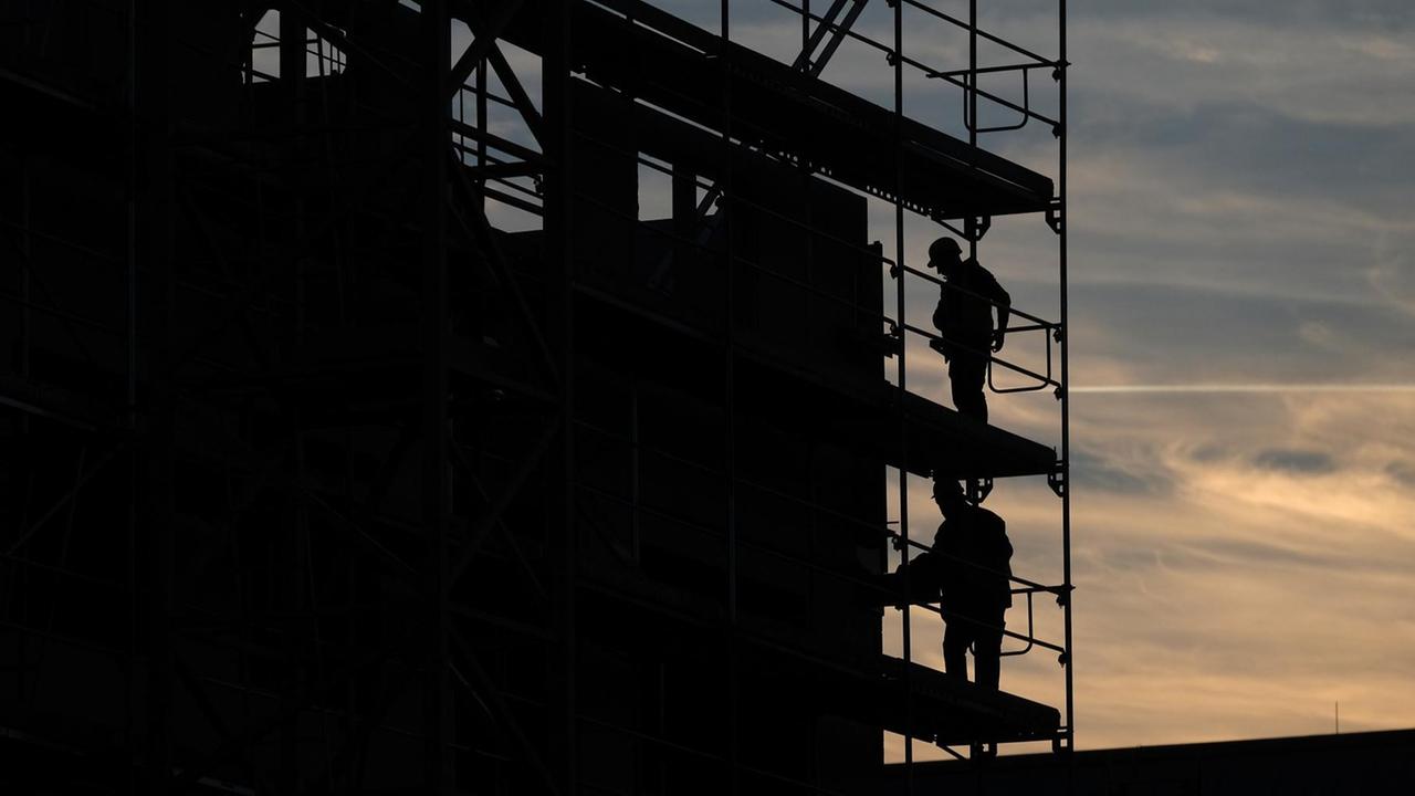 Auf einer Berliner Baustelle stehen Arbeiter auf dem Baugerüst.