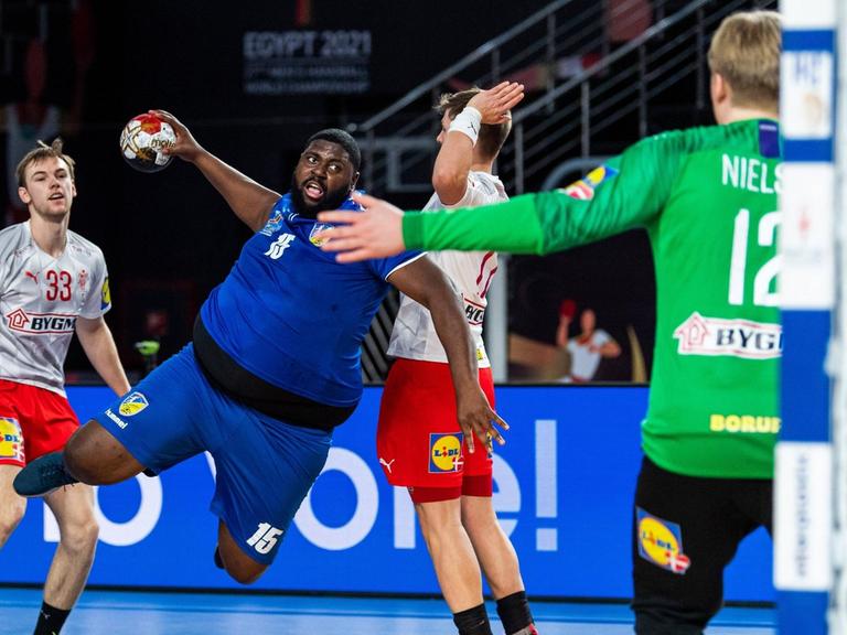 Der kongolesische Handballnationalspieler Gauthier Mvumbi (m) im WM-Spiel gegen Dänemark am 17. Januar in Kairo. Ein Handballspieler versucht mit einem Sprungwurf ein Tor zu erzielen.