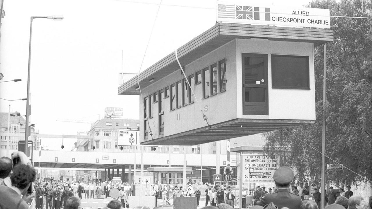 Abbau des Checkpoint Charlie, Berlin am 22. Juni 1990. Mit einem Kran wird das ehemalige Wärterhäuschen zum Abtransport angehoben. 