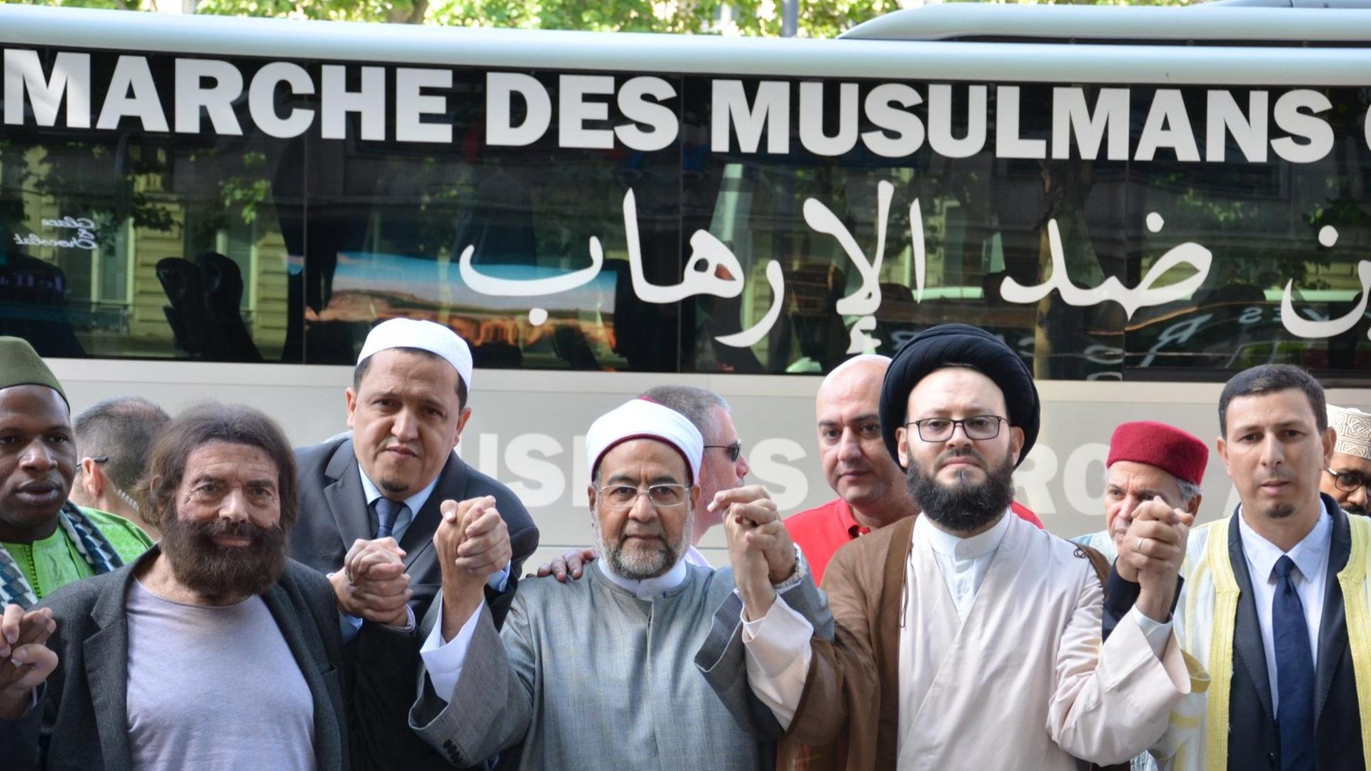 Imame beten am 08.07.2017 vor einem Bus mit der Aufschrift _Marsch der Muslime gegen den Terrorismus_ auf dem Prachtboulevard Champs-Élysées in Paris