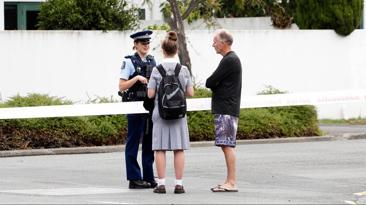 Eine Polizistin spricht in der Nähe einer angegriffenen Moschee in Christchurch mit zwei Anwohnern. Das Gelände ist mit einem Band abgesperrt.