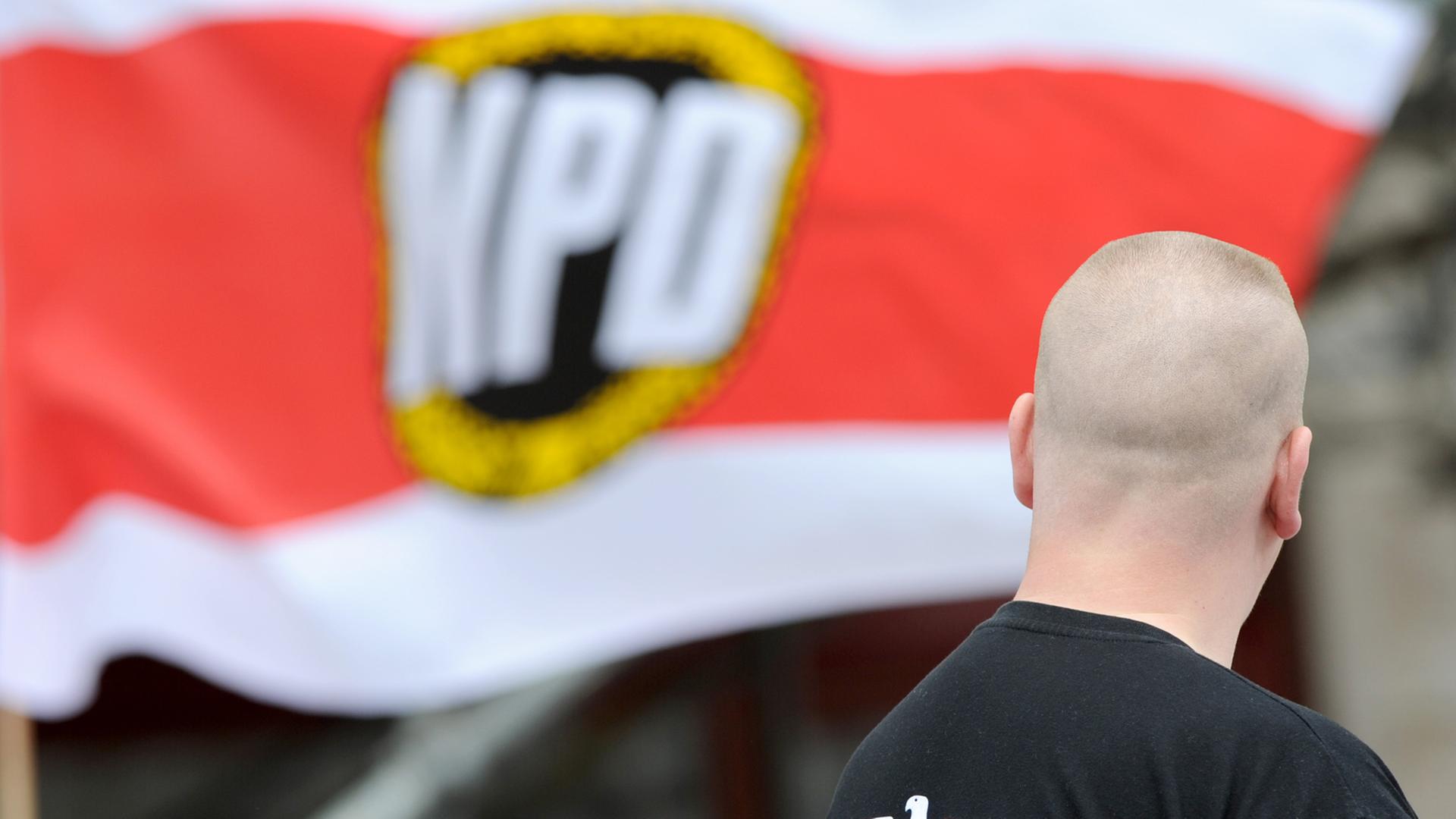 Mann mit Glatze vor NPD-Flagge