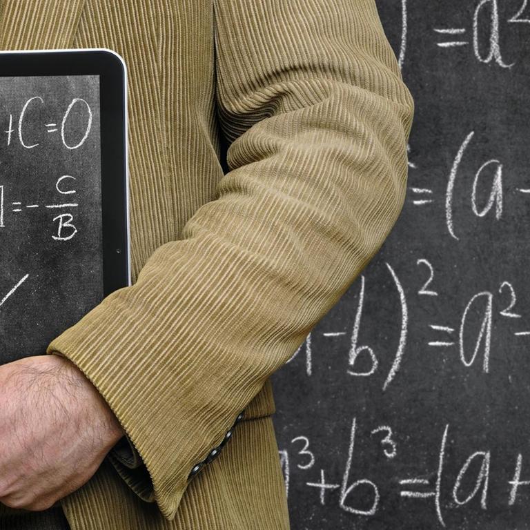 Lehrer hält einen Tablet-Computer vor einer Tafel, auf dem eine Tafel abgebildet ist. 