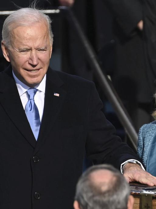 Joe Biden wird als US-Präsident vereidigt und schwört auf die Bibel, rechts von ihm steht seine Ehefrau.