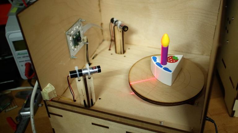 Eine Holzspielzeugtorte mit Kerze steht in einem Scanner