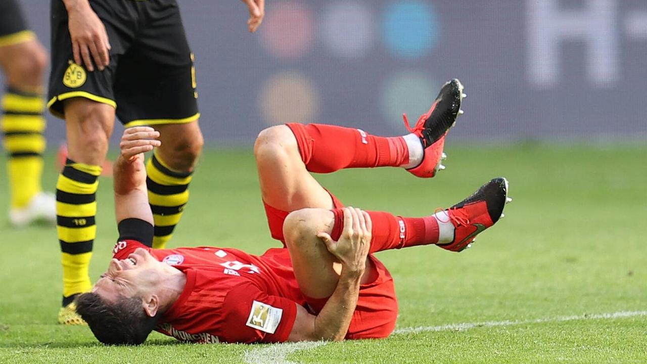 Der Fussballspieler Robert Lewandoski vom FC Bayern München liegt nach einem Foul von Łukasz Piszczek (Borussia Dortmund) am Boden.