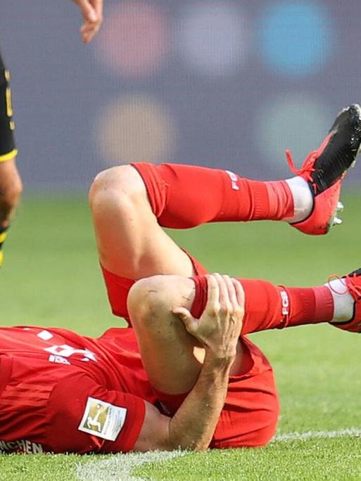 Der Fussballspieler Robert Lewandoski vom FC Bayern München liegt nach einem Foul von Łukasz Piszczek (Borussia Dortmund) am Boden. Der Fussballspieler Robert Lewandoski vom FC Bayern München liegt nach einem Foul von Łukasz Piszczek (Borussia Dortmund) am Boden.
