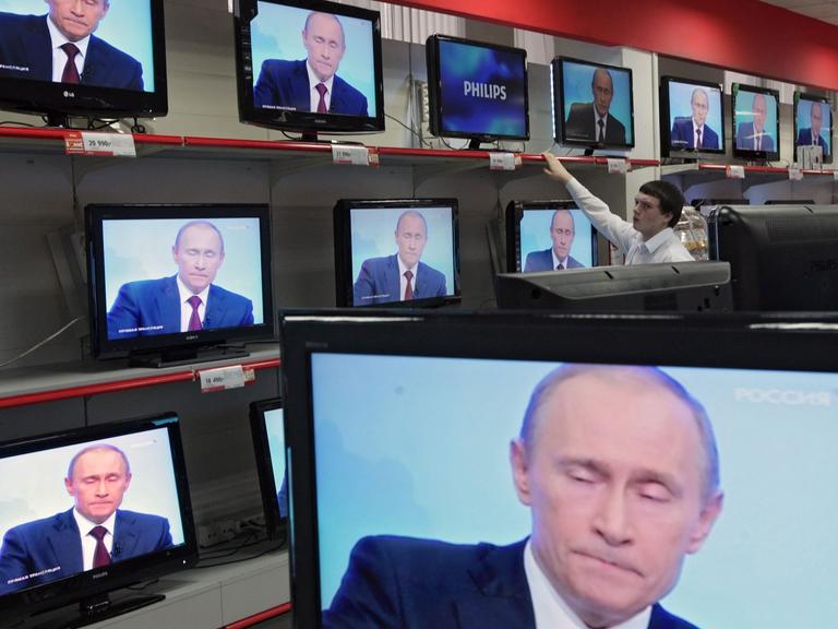 Wladimir Putin ist in einem Geschäft auf diversen TV-Bildschirmen zu sehen.