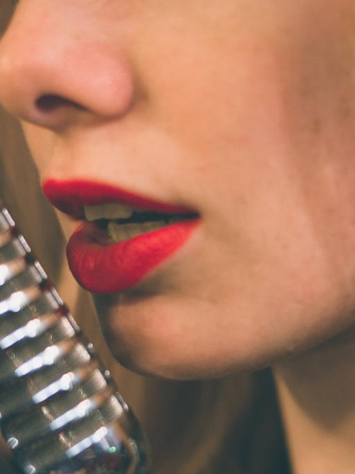 Die roten Lippen einer Sängerin vor einem Studiomikrophon