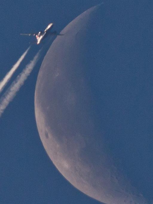 Ein Flugzeug fliegt über Nürnberg (Bayern) scheinbar am Mond vorbei.
