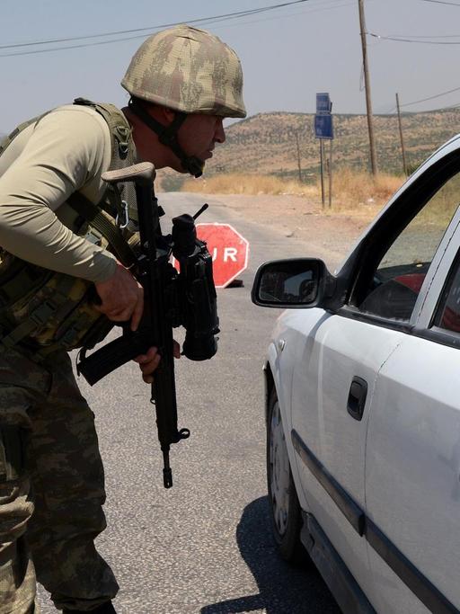 An einem Kontrollpunkt der türkischen Armee in Diyabakir an der Grenze zu Syrien überprüft ein Soldat mit Maschinengewehr einen Autofahrer.