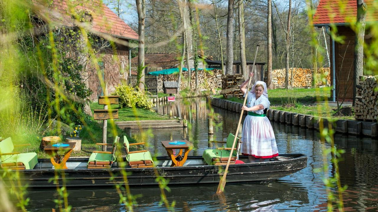 Eine Kahnfährfrau steht in sorbisch-wendischer Festtagstracht auf einem Spreewaldkahn.