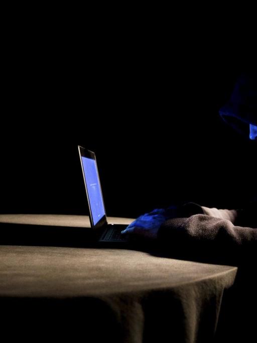 Ein Hacker mit Kapuzenpullover arbeitet an seinem Laptop