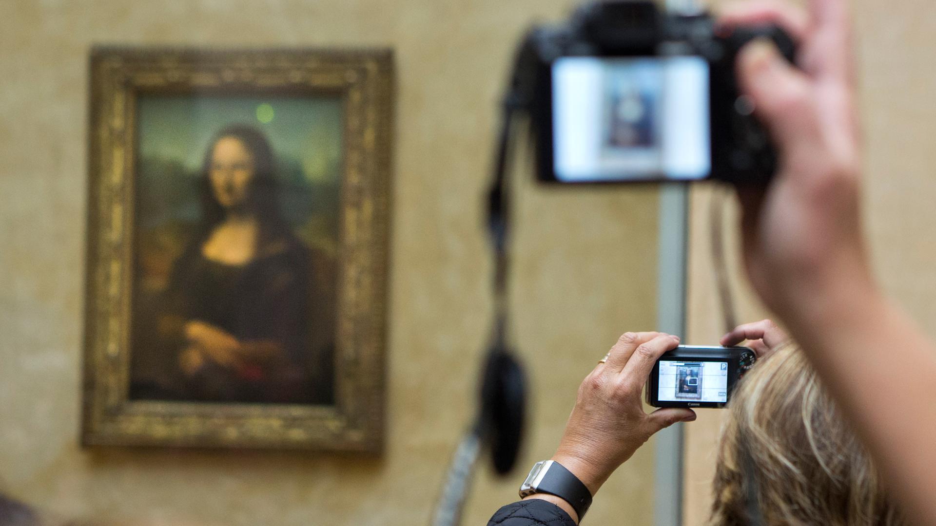 Besucher des Louvre in Paris machen Fotos der Mona Lisa von Leonardo da Vinci .