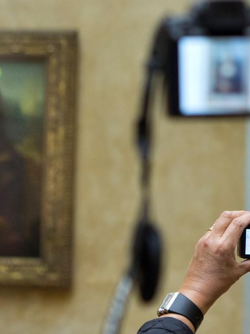 Besucher des Louvre in Paris machen Fotos der Mona Lisa von Leonardo da Vinci .