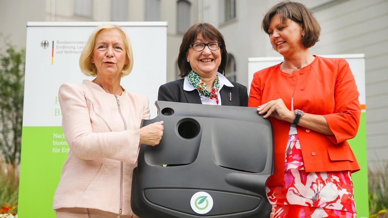 Christine Lang (m.) vom Bioökonomierat, Forschungsministerin Wanka (l.) und Agrarministerin Aigner präsentieren eine Motorabdeckung aus Bioplastik.