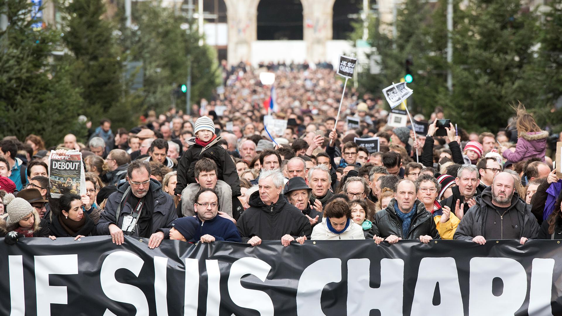Menschen halten bei ihrem Trauer- und Gedenkmarsch in Lille ein Banner mit dem Schriftzug "Je suis Charlie" (Ich bin Charlie" hoch.