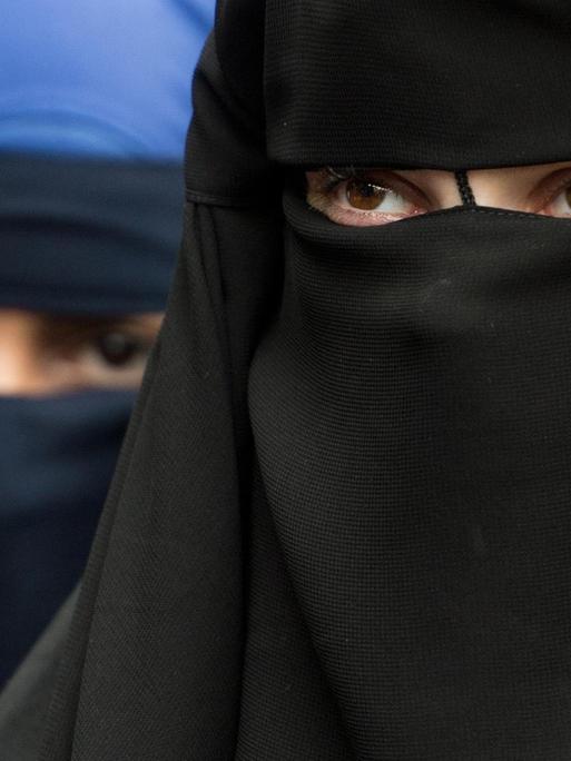 Zwei vollverschleierte Frau schauen durch die Schlitze ihrer Nikabs.