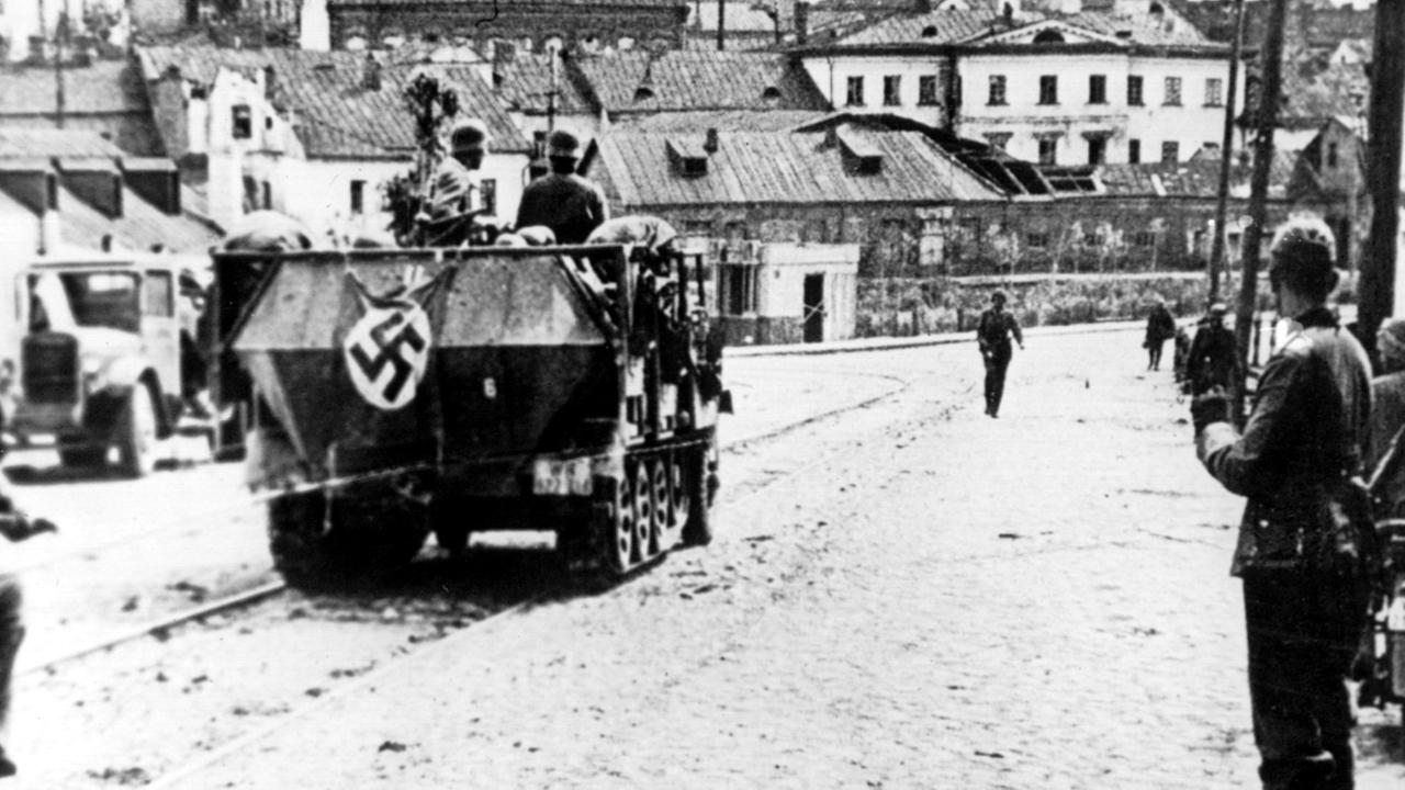 Ein Panzerfahrzeug der Wehrmacht, gefolgt von Soldaten auf Motorrädern, in der Stadt Minsk während des Rußland-Feldzuges im August 1941.