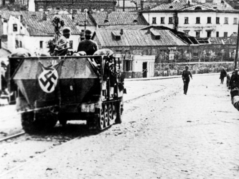 Ein Panzerfahrzeug der Wehrmacht, gefolgt von Soldaten auf Motorrädern, in der Stadt Minsk während des Rußland-Feldzuges im August 1941.