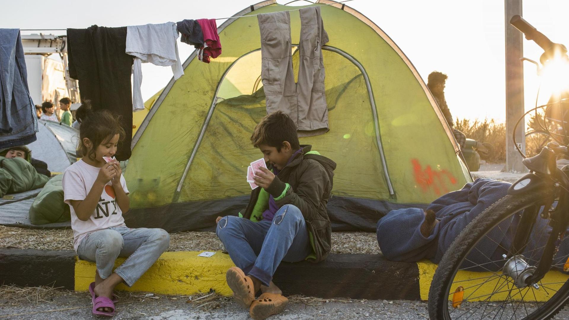 Kinder spielen Karten am Straßenrand in der Nähe des ausgebrannten Flüchtlingslagers Moria