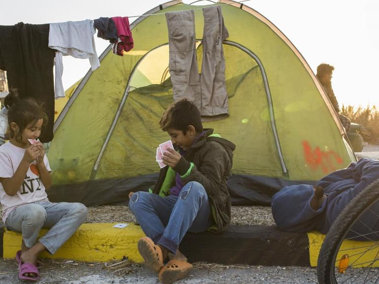 Kinder spielen Karten am Straßenrand in der Nähe des ausgebrannten Flüchtlingslagers Moria