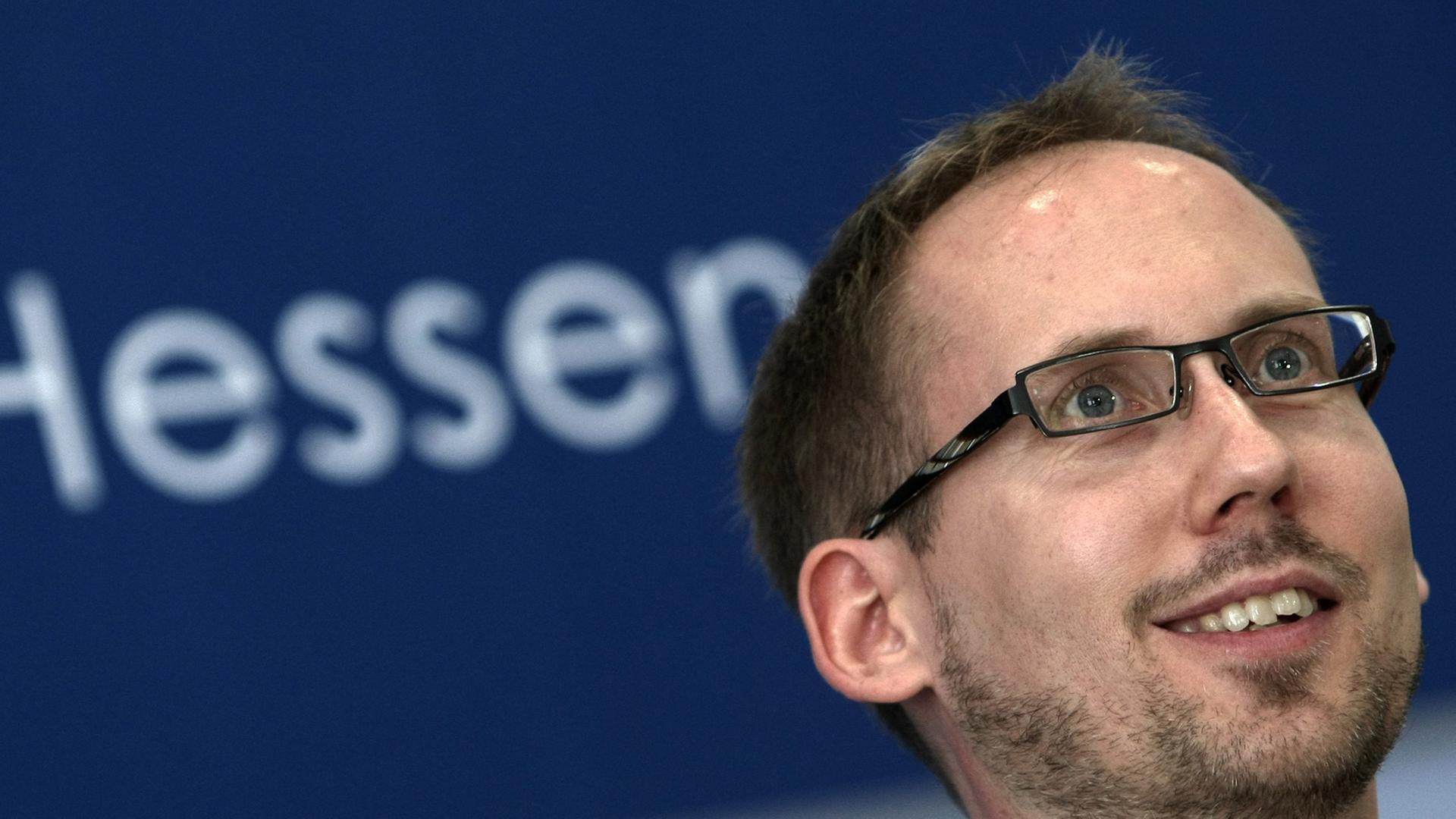 Kai Klose, der Landesvorsitzender der hessischen Grünen, in einem Raum vor dem Schriftzug "Hessen"
