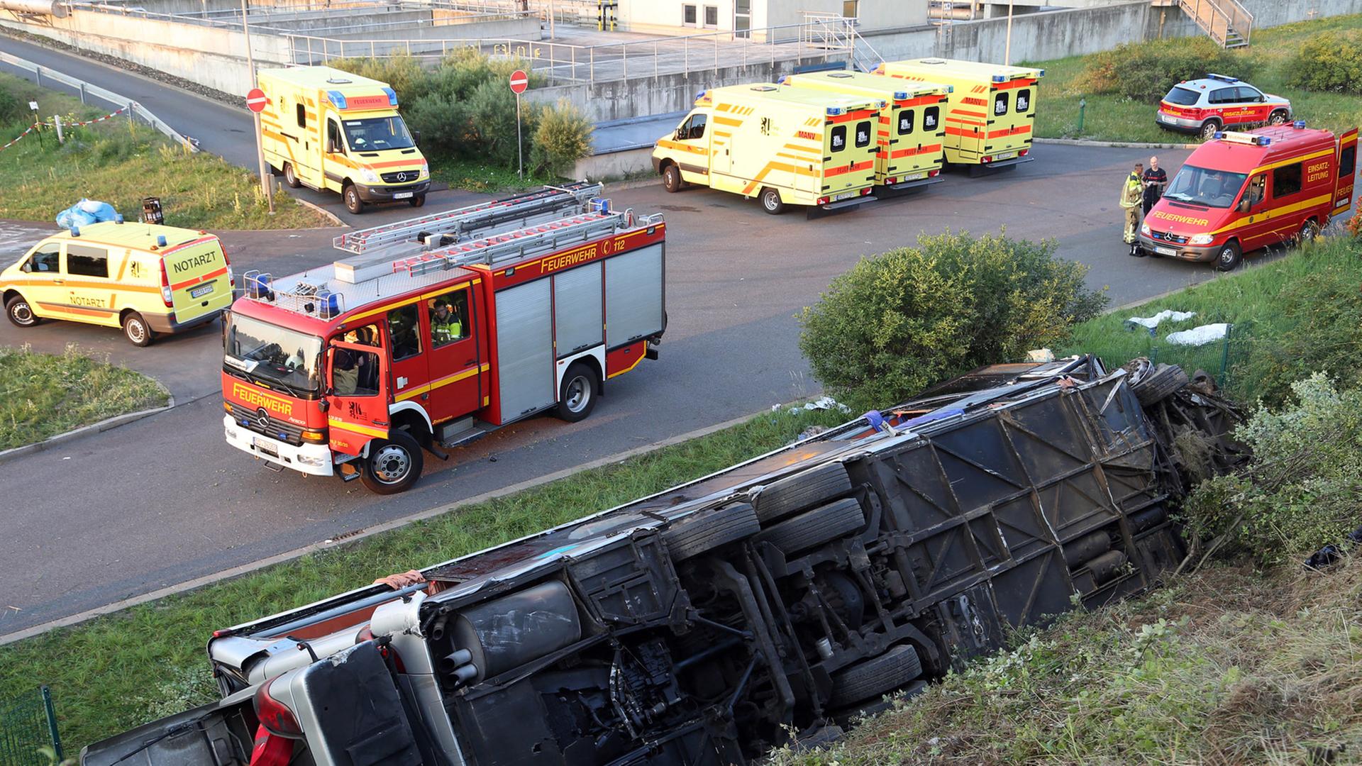 Ein Reisebus liegt umgekippt an einer Böschung. Feuerwehr- und Rettungswagen im Hintergrund. Ein Reisebus liegt umgekippt an einer Böschung. Feuerwehr- und Rettungswagen im Hintergrund.