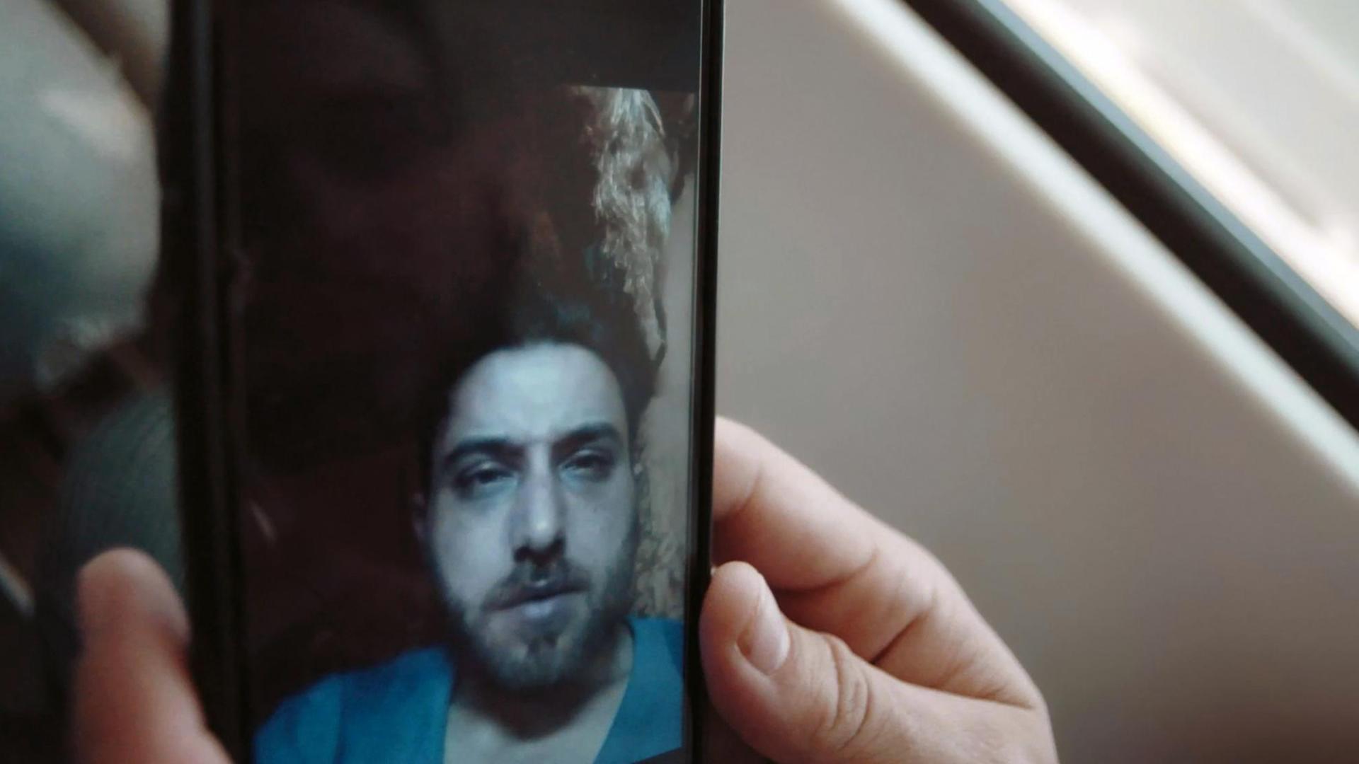 Szene aus "Nachrichten aus Syrien – The war on my phone": Ein syrischer Häftling erzählt einem geflohenen Bekannten in Deutschland mit Hilfe eines eingeschmuggelten Smartphones aus dem Gefängnis über seine Lebensumstände