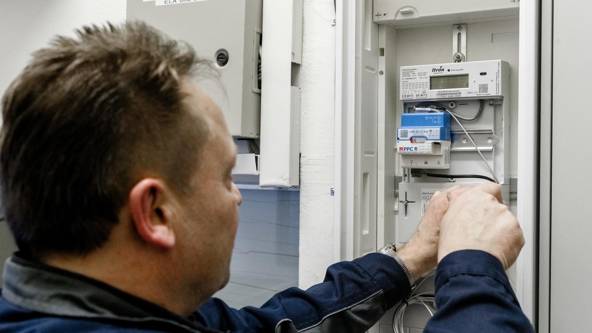 Ein Elektriker montiert einen digitalen Stromzähler mit einem Smart-Meter-Gateway zur Datenübertragung.