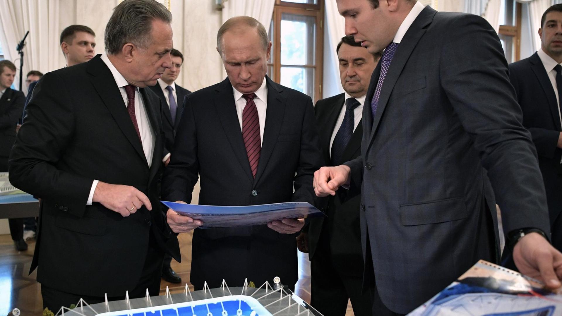 Russian President Vladimir Putin (2nd L), accompanied by deputy prime minister Vitaly Mutko (L), visits an exhibition devoted to the preparation for the 2018 FIFA World Cup at the Kremlin in Moscow on October 3, 2017. / AFP PHOTO / SPUTNIK / Alexey NIKOLSKY
