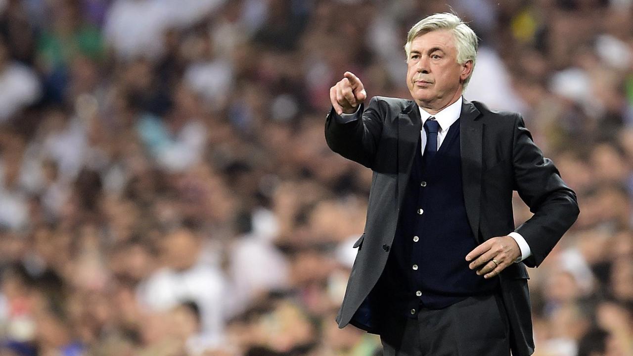 Carlo Ancelotti steht in einem schwarzen Anzug während eines Spiels am Spielfeldrand und gestikuliert.