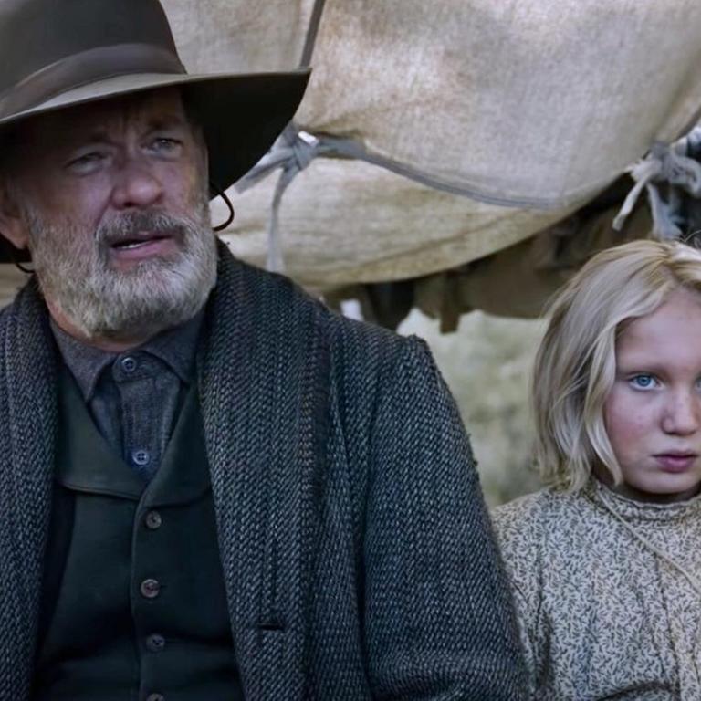Szene aus dem Western „Neues aus der Welt“ von Paul Greengrass. Tom Hanks und Helena Zengel sitzen auf einer Kutsche und blicken nach vorn.