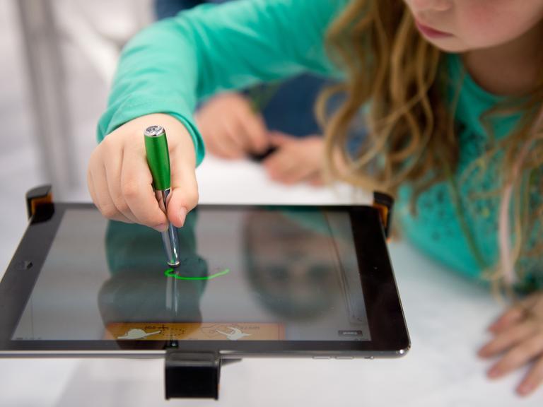 Ein Mädchen arbeitet auf der Bildungsmesse "Didacta" in Stuttgart an einem iPad.