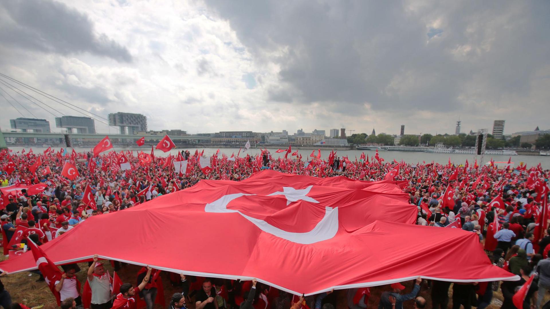 Anhänger des türkischen Staatspräsidenten Erdogan schwenken am 31.07.2016 in Köln Fahnen. Doch es gibt auch genug Gegner.