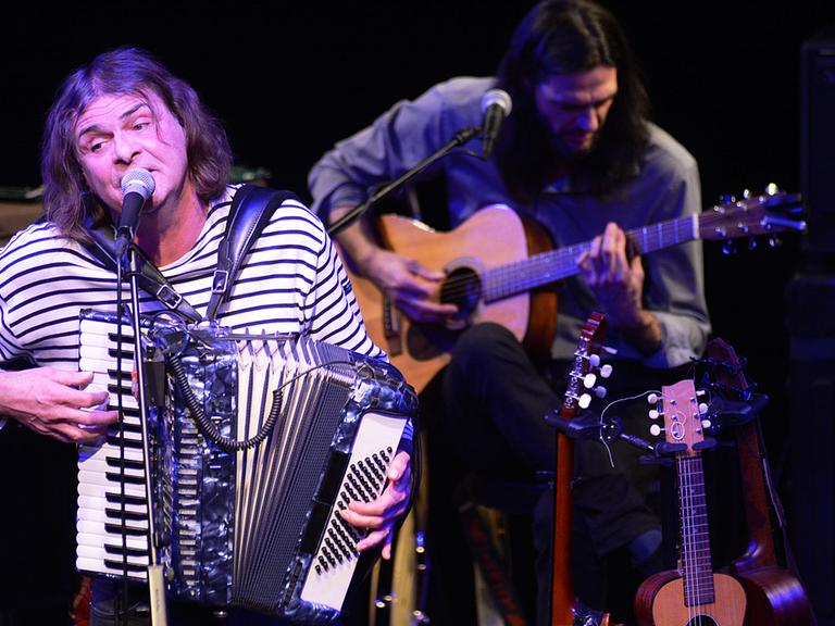Hans Eckhardt Wenzel spielt Akkordeon, im Hintergrund spielt ein Gitarrist seiner Band
