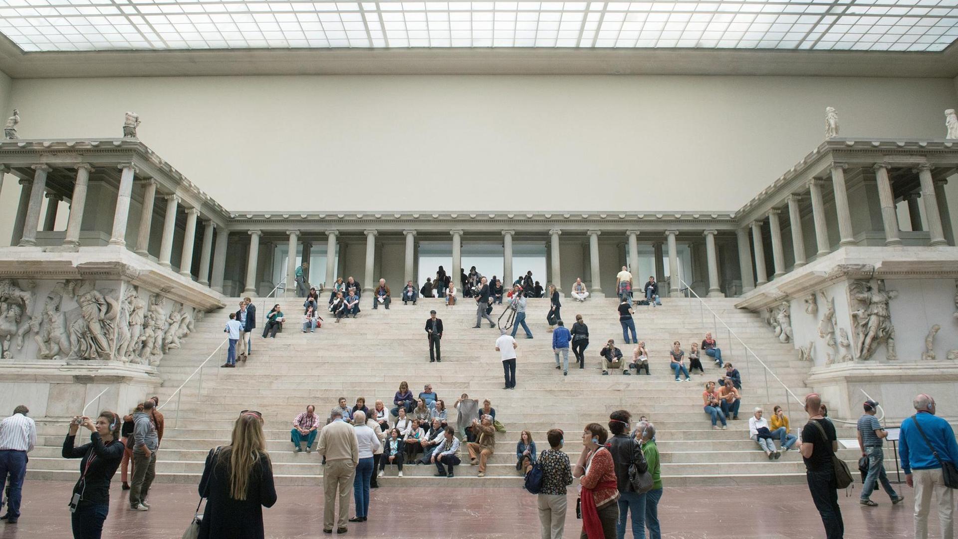 Ansicht des Pergamonaltars im Pergamonmuseum in Berlin. Auf den Stufen sitzen und stehen Museumsbesucher. Quelle: picture alliance