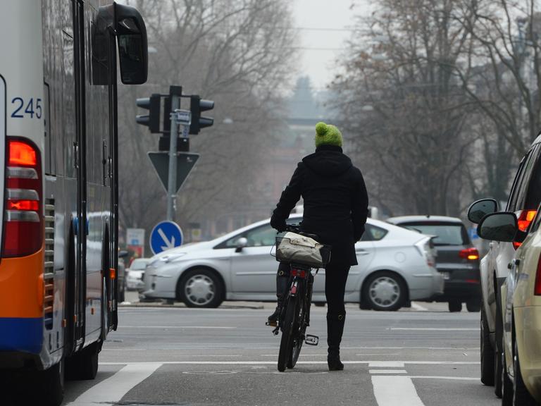 Eine Frau steht am 18.02.2015 in Wiesbaden (Hessen) mit ihrem Fahrrad an einer belebten Kreuzung.