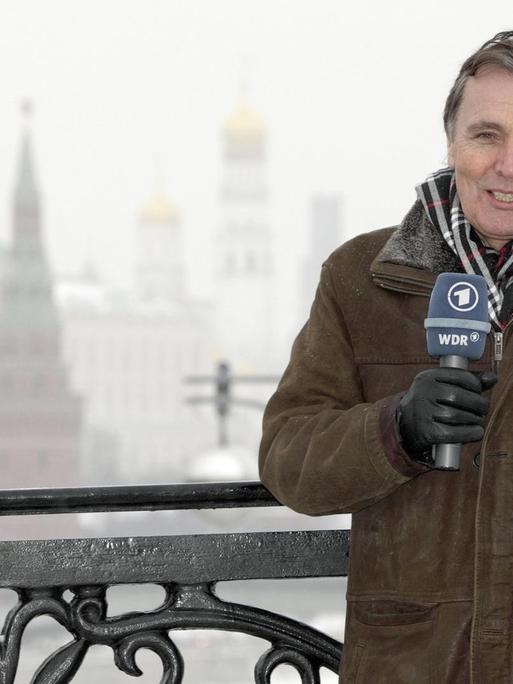 Hermann Krause steht mit einem Mikrofon der ARD vor einer verschneiten Winderlandschaft in Moskau.