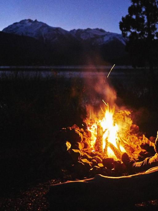 Menschen an einem Lagerfeuer in der Natur bei Nacht